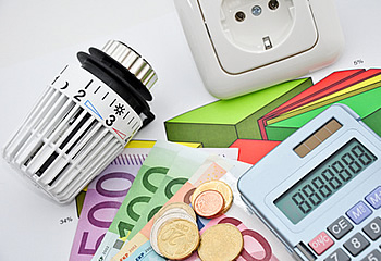 Taschenrechner und Geld neben Thermostat und Steckdose